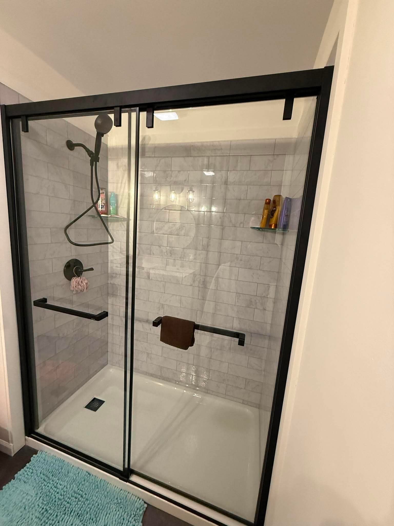 Walk-in shower with marble subway tile and black glass doors