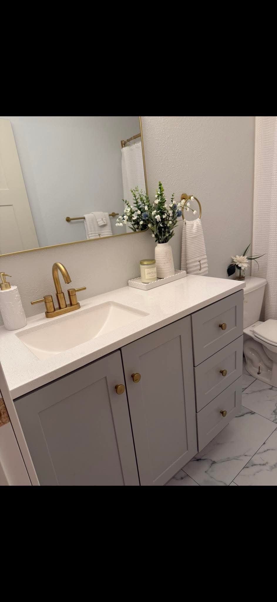 Gray vanity with gold faucet and marble tile floor