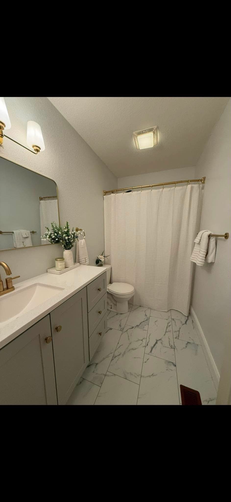 Bathroom remodel with gray vanity and gold fixtures