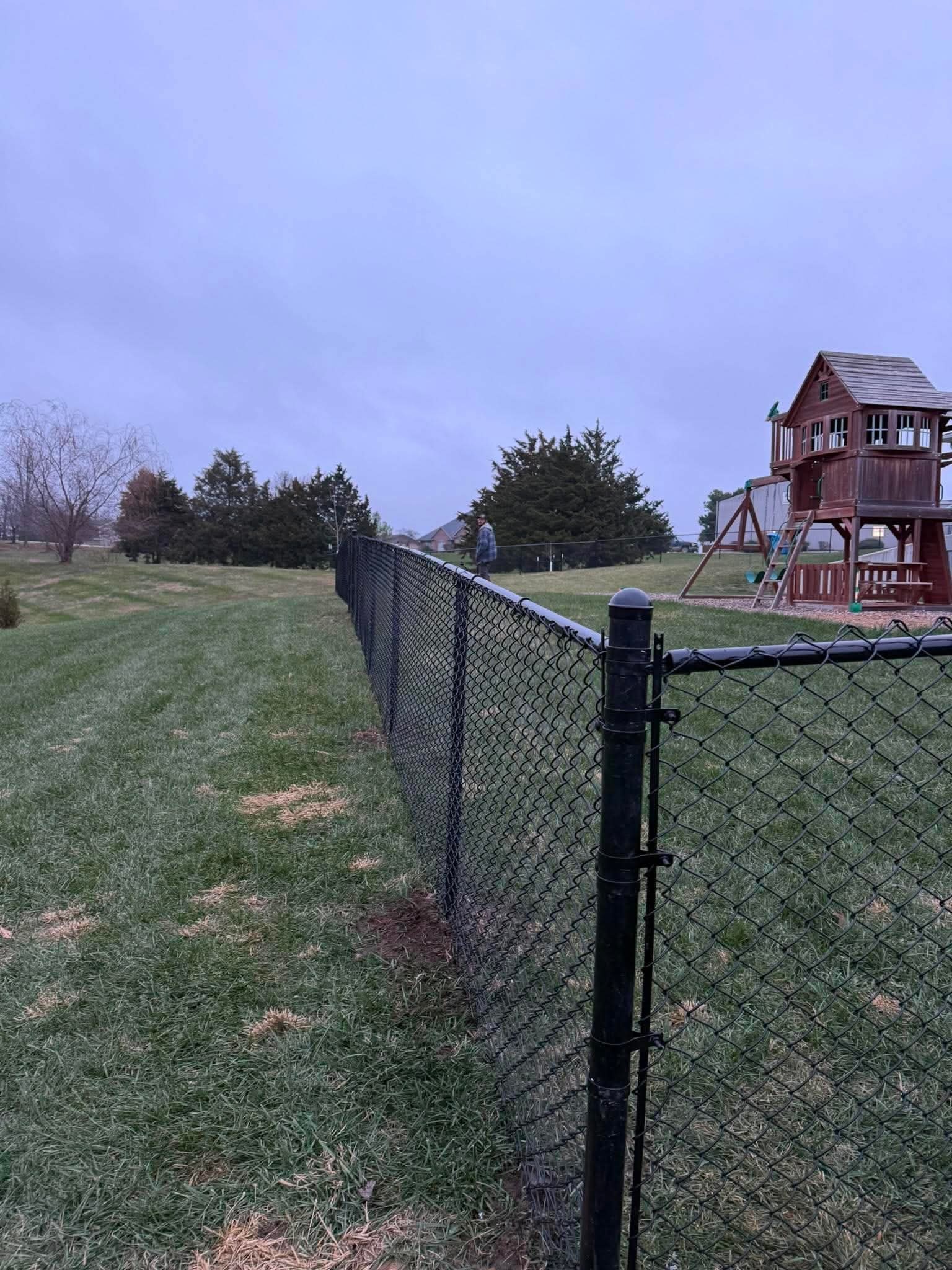 Black chain-link fence with backyard playset
